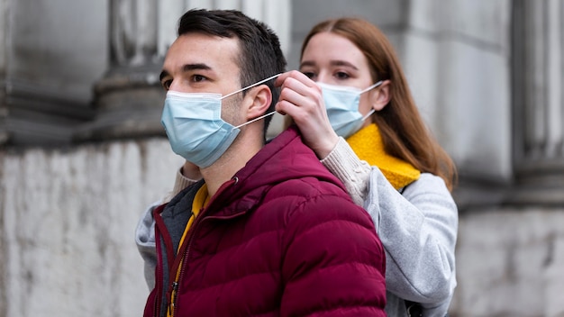 Kostenloses Foto paar in der stadt, die zusammen medizinische masken trägt