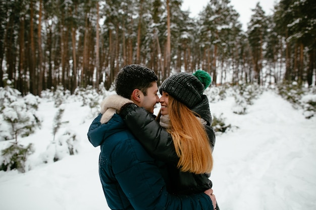 Paar in der Winterkleidung gehend in einen schneebedeckten Wald. Winter Liebesgeschichte.