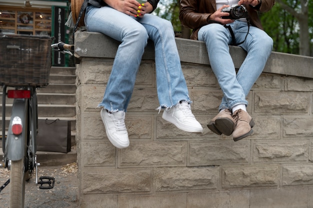 Kostenloses Foto paar in kunstlederjacken sitzt auf betonzaun im freien