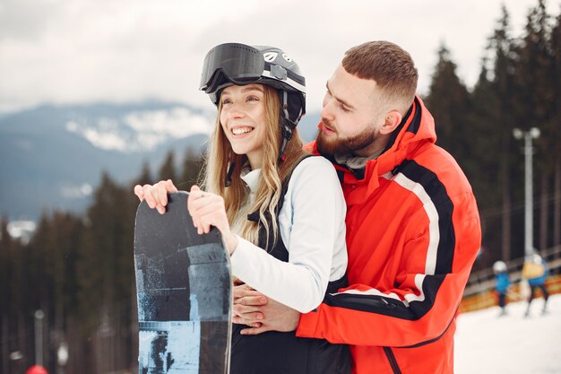 Paar in Snowboardanzügen. Sportler auf einem Berg mit einem Snowboard in den Händen am Horizont. Konzept zum Sport