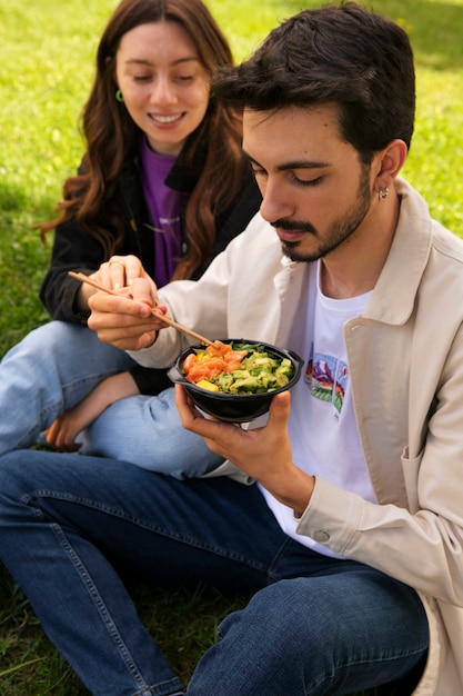 Paar isst eine Schüssel Lachs auf dem Rasen im Freien