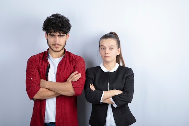 Paar junge Freunde, die Arme auf weißem Hintergrund gekreuzt stehen. Hochwertiges Foto