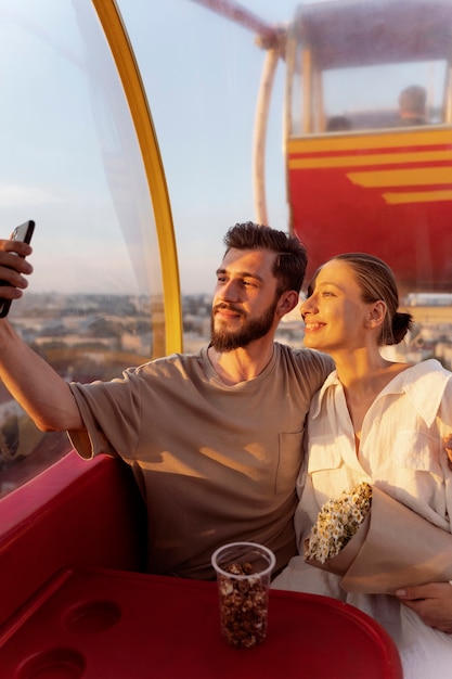 Paar macht Selfie, während es gemeinsam am Riesenrad unterwegs ist