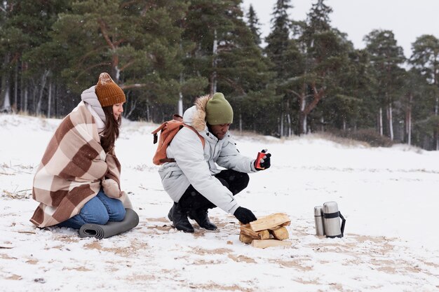 Paar macht während eines Winter-Roadtrips ein Feuer am Strand, um sich aufzuwärmen