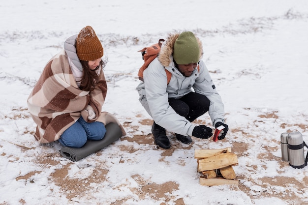 Paar macht während eines Winter-Roadtrips ein Feuer am Strand, um sich aufzuwärmen