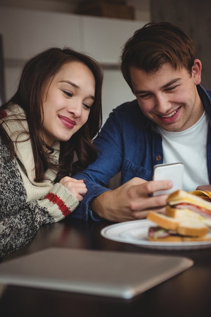 Paar mit Handy beim Frühstück