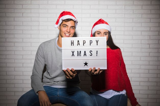 Paar mit Happy Christmas Zeichen