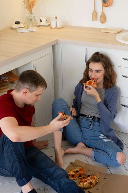 Paar mit mittlerem Schuss, das Pizza isst