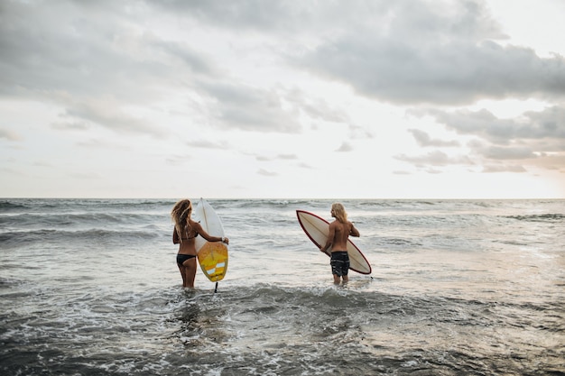 Paar posiert am Strand und geht surfen