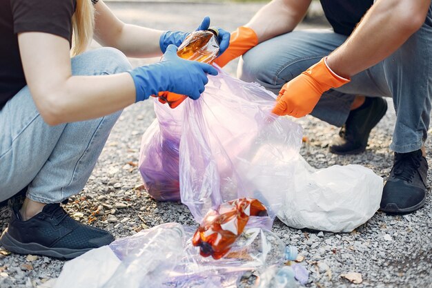 Paar sammelt Müll in Müllsäcken im Park