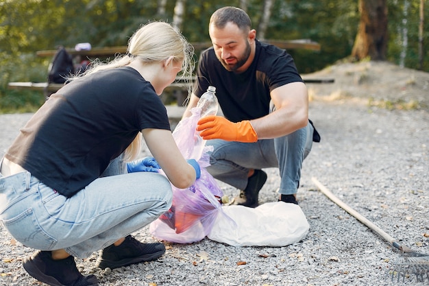 Paar sammelt Müll in Müllsäcken im Park