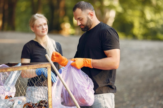 Kostenlose Foto paar sammelt müll in müllsäcken im park