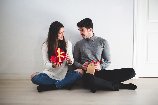 Paar sitzt auf dem Boden und sie mit einem roten Geschenk