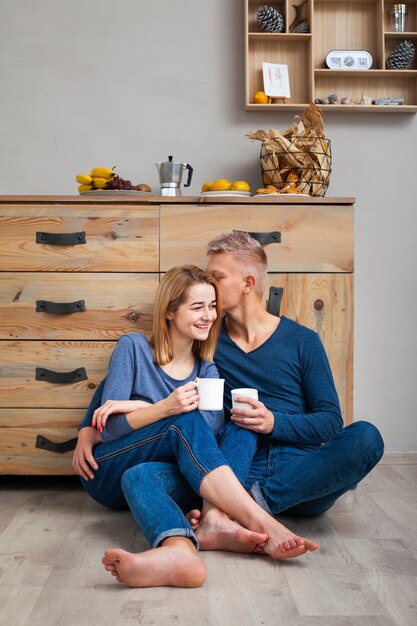 Paar sitzt auf dem Boden und trinkt eine Tasse Kaffee