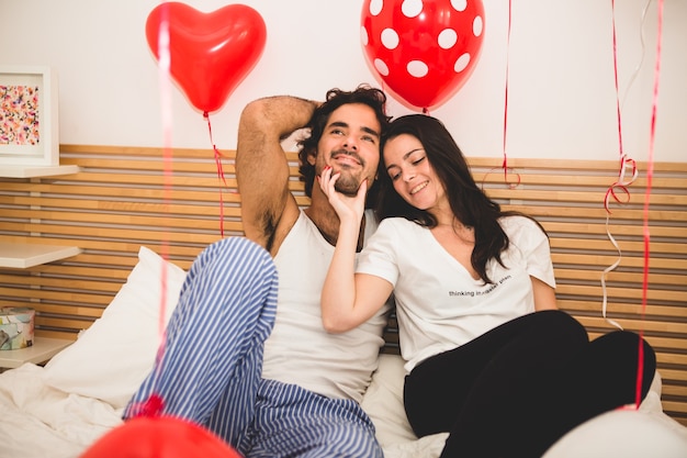 Paar sitzt auf einem Bett mit Ballons überall