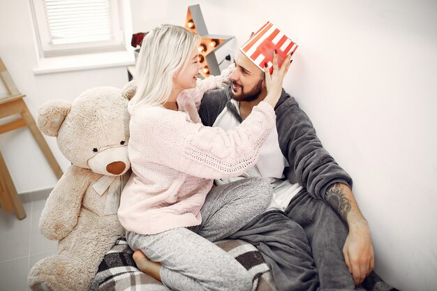 Paar sitzt auf einem Bett mit großem Teddybär und Eimer Popcorn