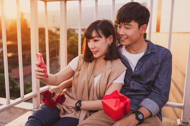 Paar sitzt zusammen mit einem roten Geschenk an der mobilen Suche