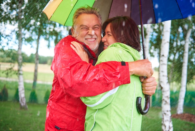 Paar steht und umarmt unter Regenschirm