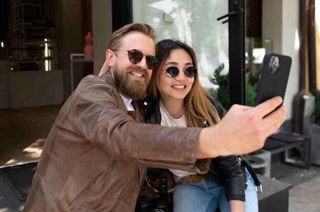 Paar trägt Kunstlederjacken und macht Selfie zusammen im Freien
