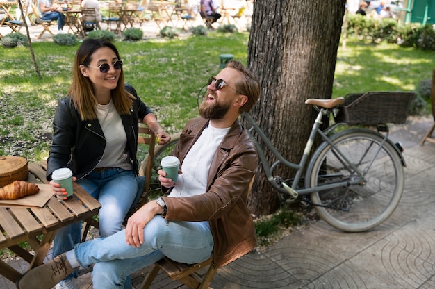 Paar trägt Kunstlederjacken und trinkt zusammen Kaffee im Freien
