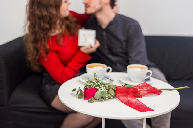 Paar umarmt in der Nähe von Tabelle mit Rose und Kaffeetassen