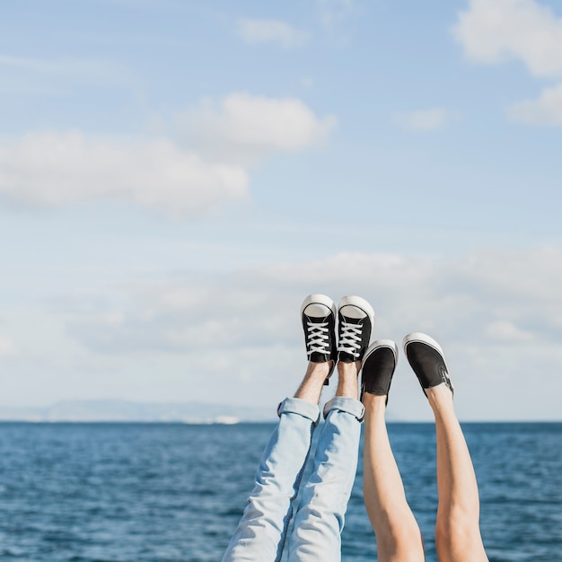 Paar- und Sommerkonzept mit den Beinen vor Meer