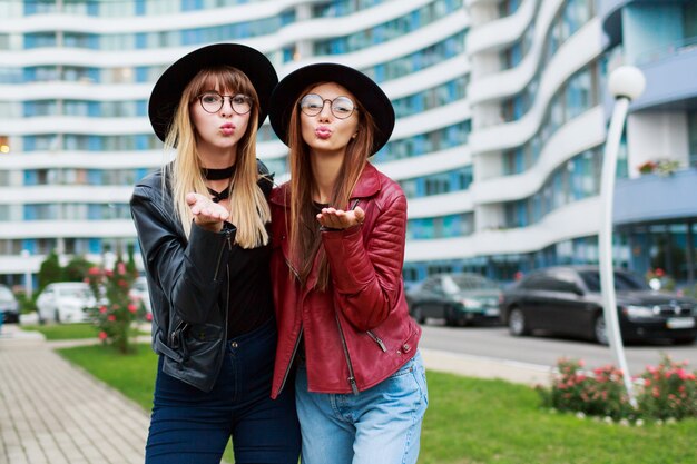 Paar von zwei stilvollen Frauen im trendigen Frühlingsoutfit, die Luftkuss senden