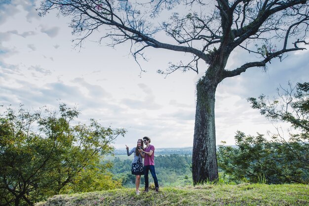 Paar vor einem Baum auf einem Hügel
