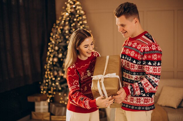 Paar zusammen mit Weihnachtsgeschenken durch den Weihnachtsbaum