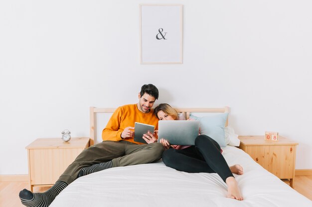 Paare auf Bett unter Verwendung der Technologien