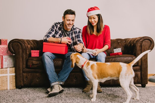 Paare auf der Couch, die Weihnachten mit Hund feiert