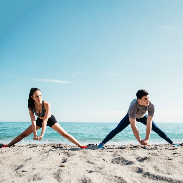 Paare, die am Strand ausdehnen