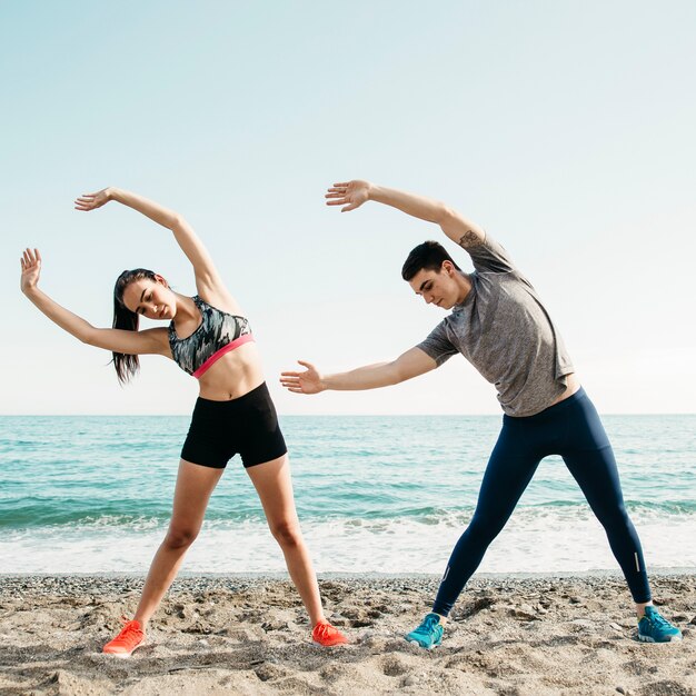 Paare, die am Strand ausdehnen