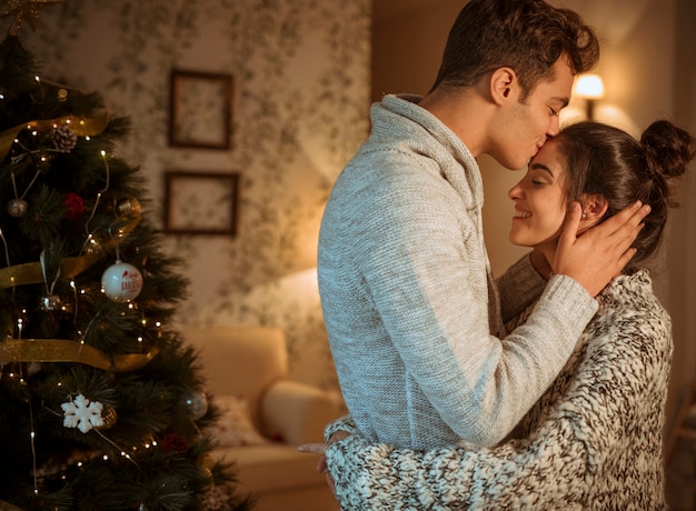 Kostenloses Foto paare, die am weihnachtsbaum streicheln