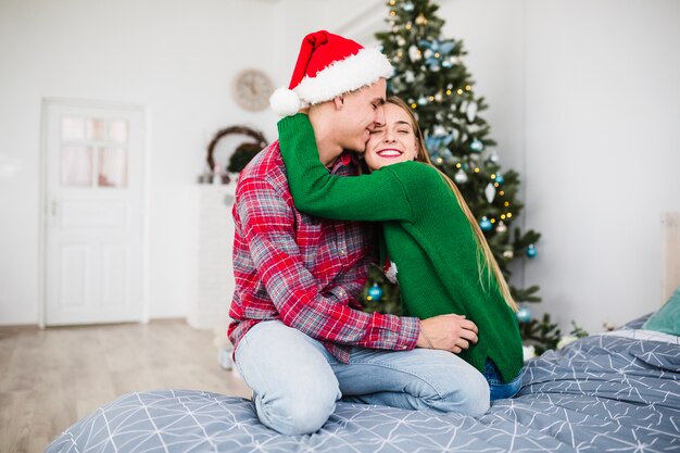 Paare, die auf Bett am Weihnachten umarmen