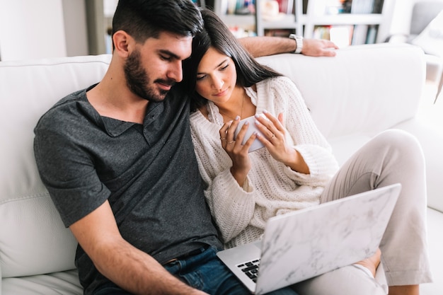 Kostenloses Foto paare, die auf dem sofa betrachtet laptop sitzen