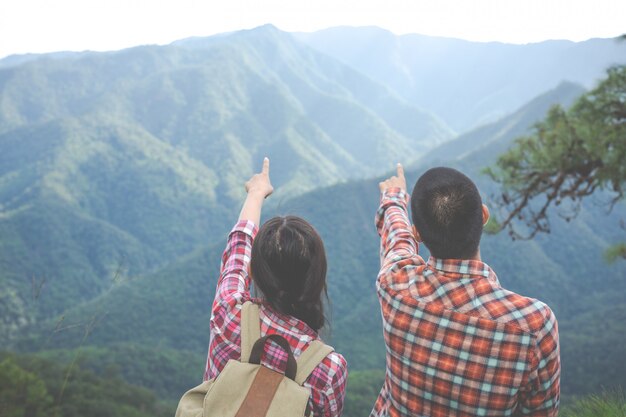 Paare, die auf die Spitze des Hügels im tropischen Wald zeigen, wandern, reisen und klettern.