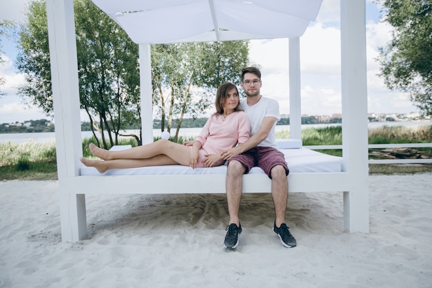 Paare, die auf einem Doppelbett am Strand umarmen