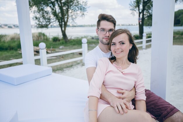 Paare, die auf einem Doppelbett am Strand umarmen