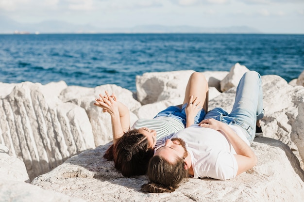 Kostenloses Foto paare, die auf felsen durch das meer liegen