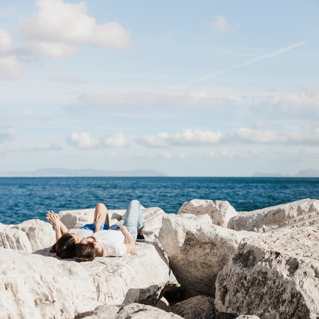 Paare, die auf Felsen in dem Meer liegen