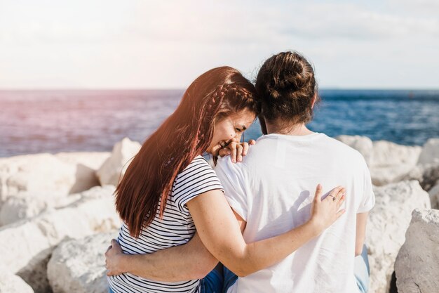 Paare, die auf Felsen in dem Meer sitzen