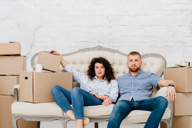 Paare, die auf Sofa nahe Kartonkästen sitzen