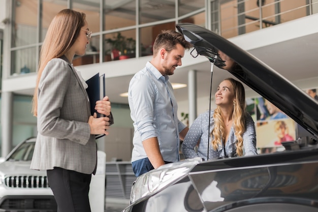 Paare, die Automotor in einem Ausstellungsraum überprüfen