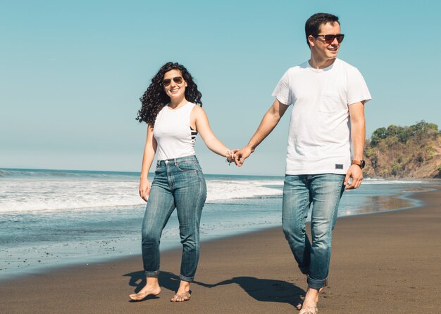 Paare, die barfuß auf sandigen Strand gehen