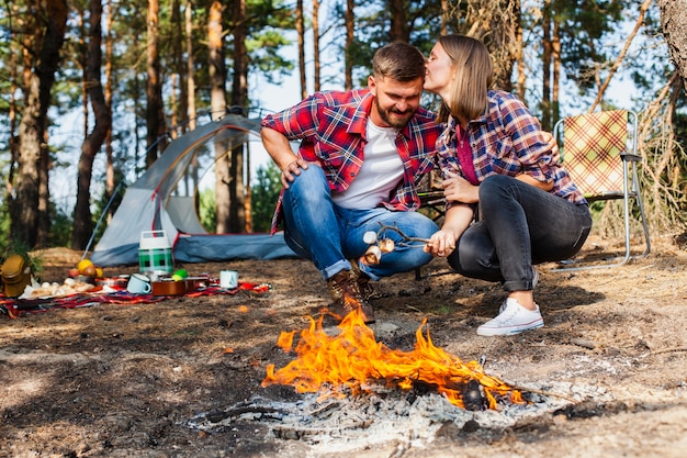 Paare, die den Eibisch am Feuer im Freien kochen