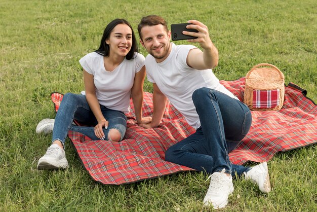 Paare, die ein selfie auf Picknickdecke nehmen