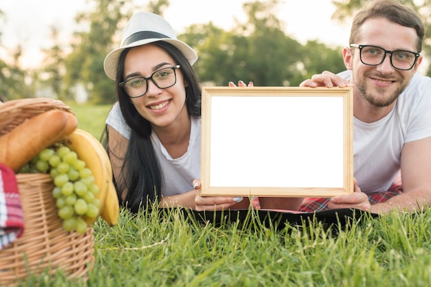 Paare, die ein whiteboard auf einer Picknickdecke zeigen