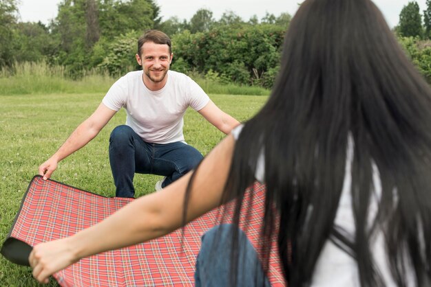 Paare, die eine Picknickdecke legen