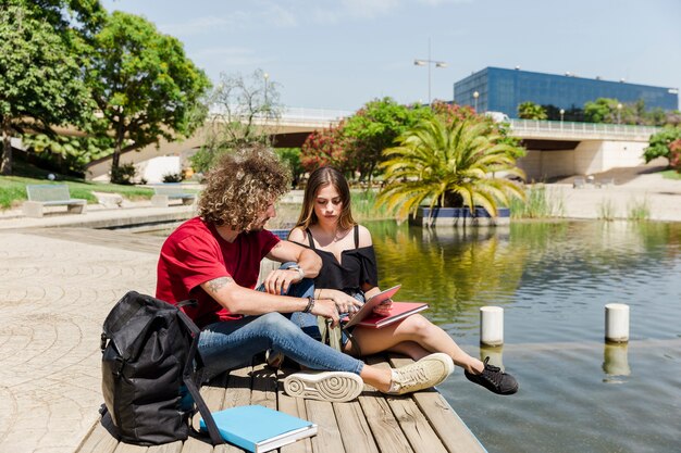 Paare, die im Park mit See studieren